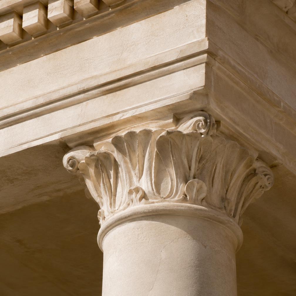 Classical stone column capital in raking sunlight